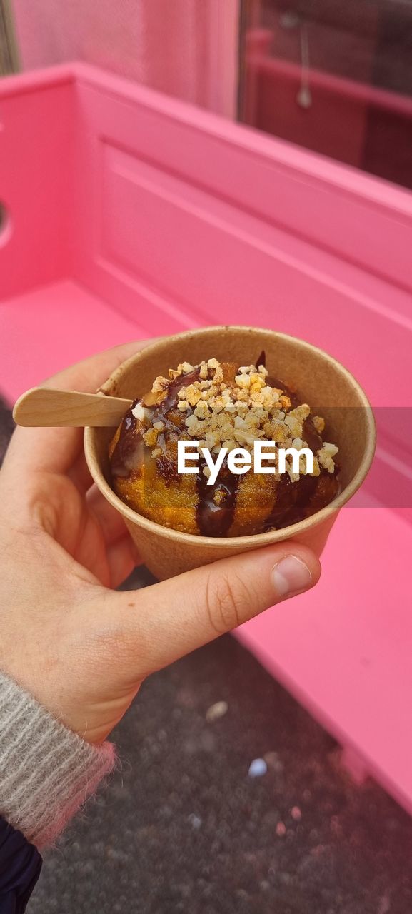 CLOSE-UP OF HAND HOLDING BOWL OF PINK CREAM