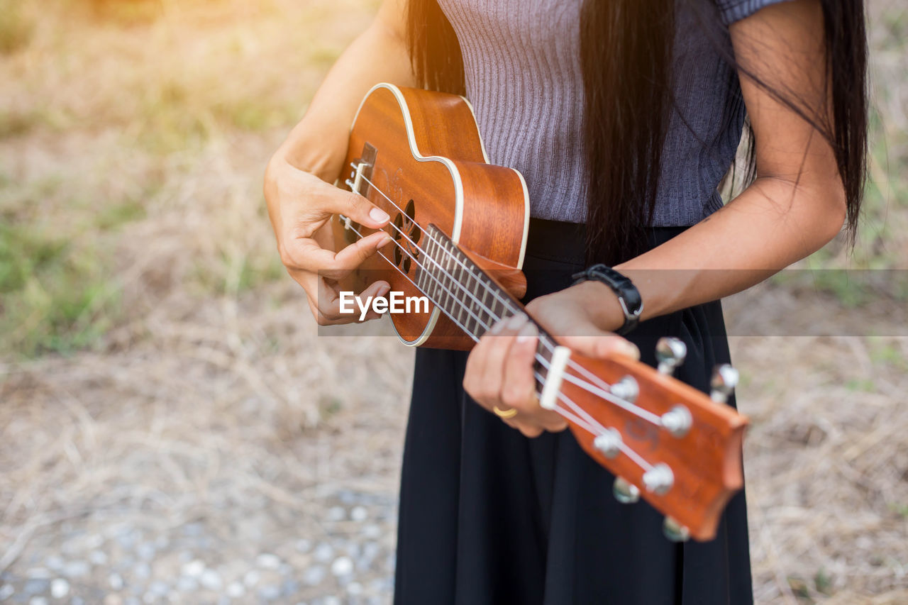 MIDSECTION OF WOMAN PLAYING GUITAR