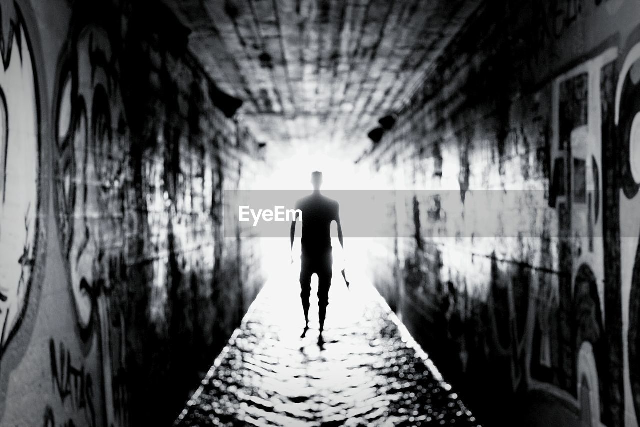 REAR VIEW OF SILHOUETTE MAN STANDING ON TUNNEL