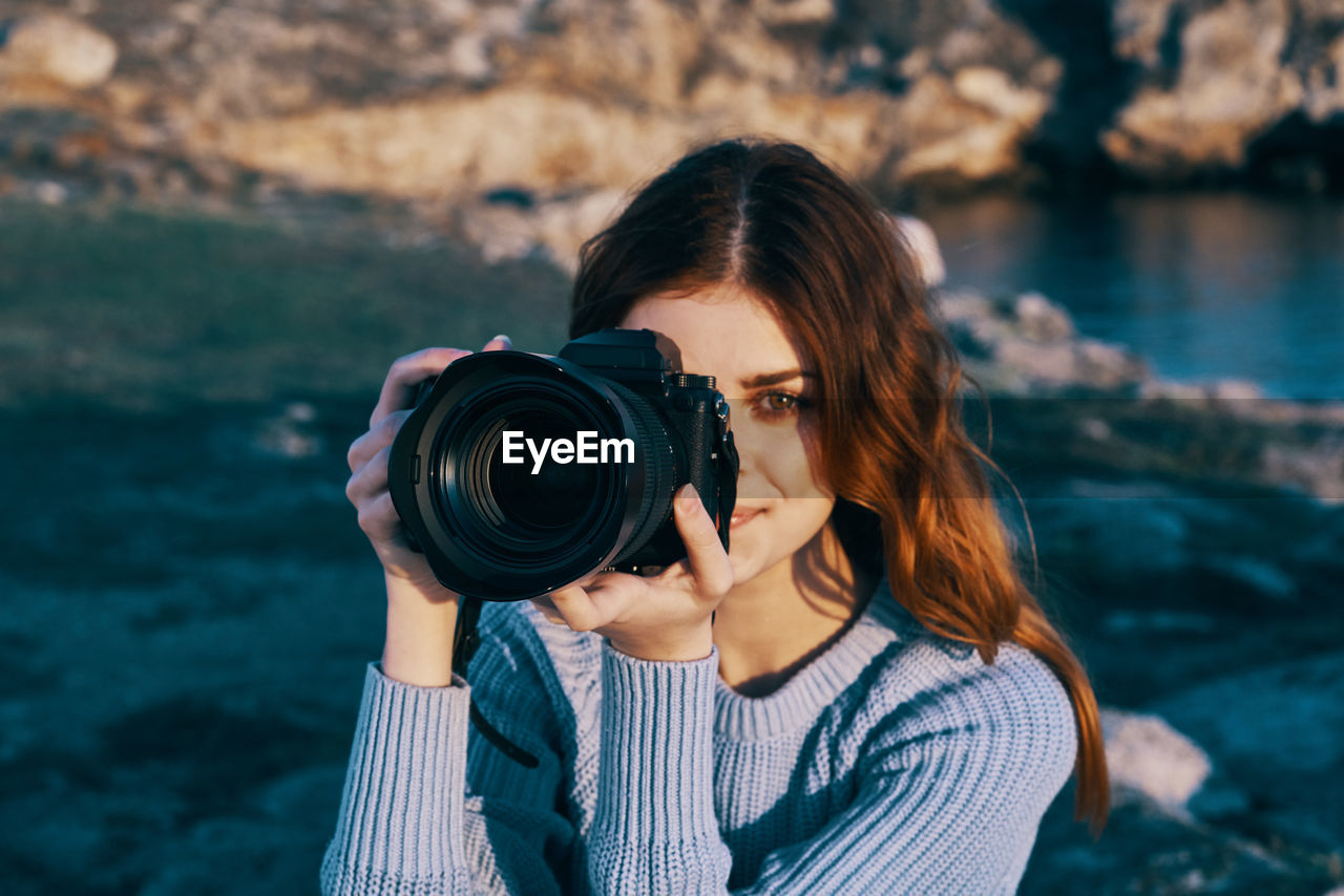 PORTRAIT OF YOUNG WOMAN PHOTOGRAPHING WITH CAMERA