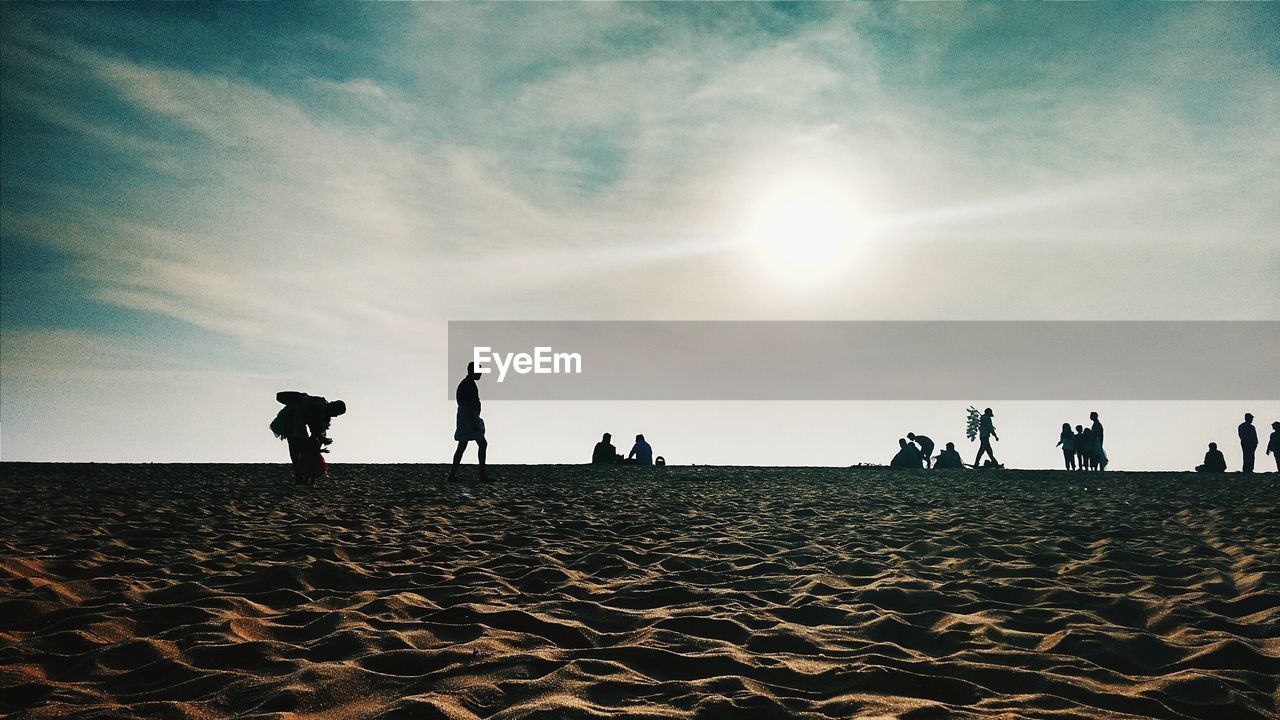 Silhouette people on sandy beach