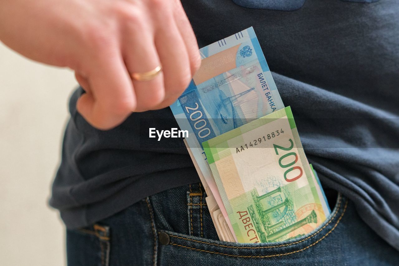 Midsection of man removing paper currencies from pocket