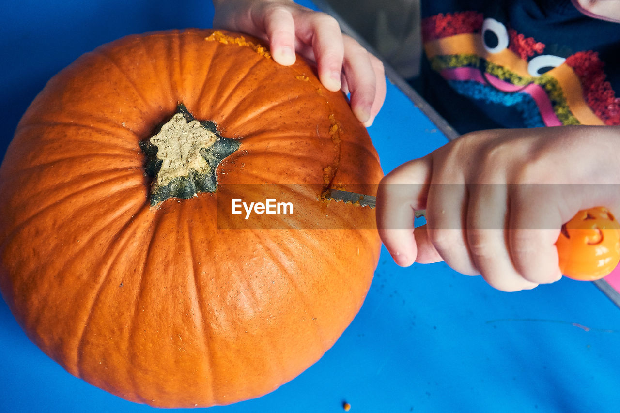 Midsection of girl cutting pumpkin at home