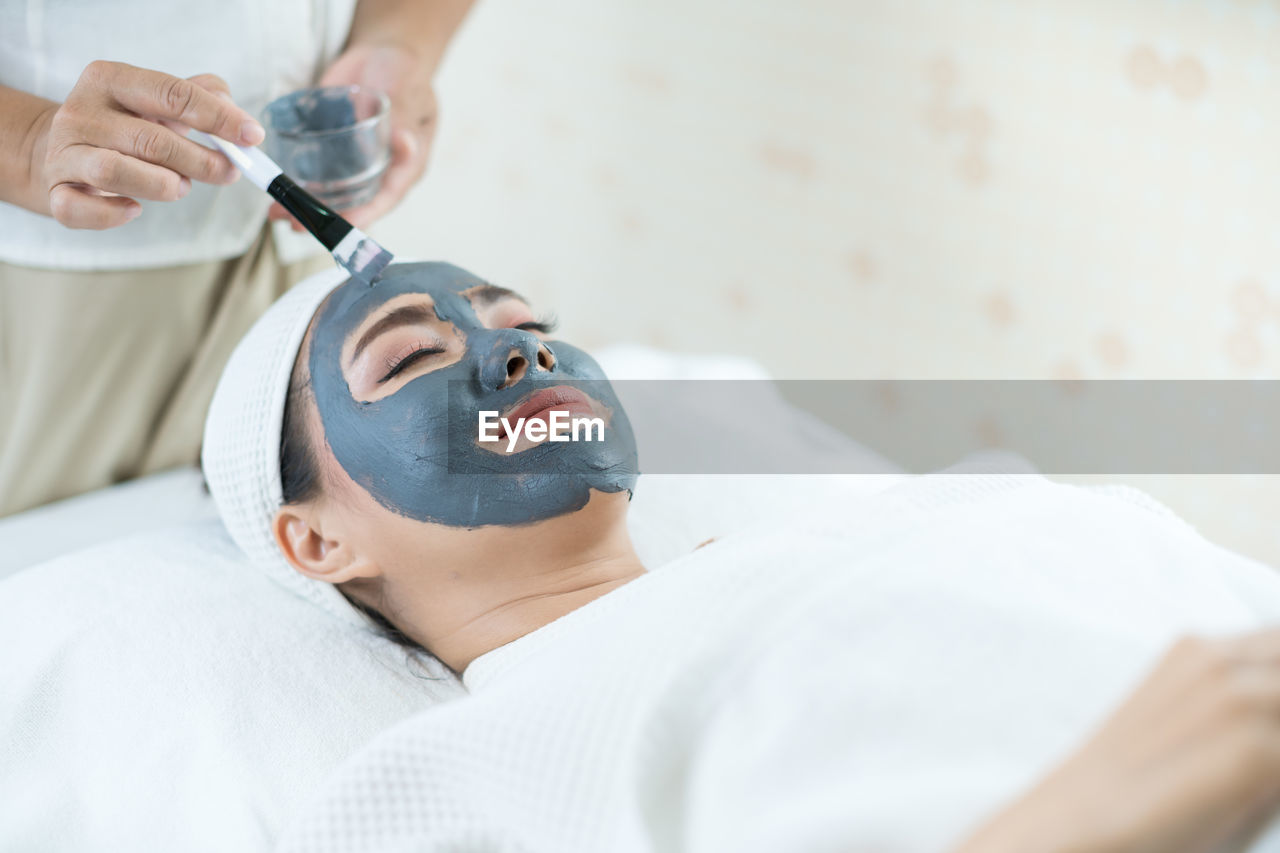 Beautiful woman masking skin in a facial spa shop