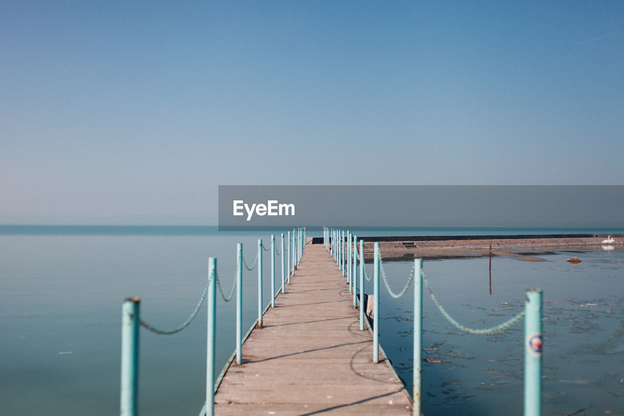 Wooden pier on sea against clear sky