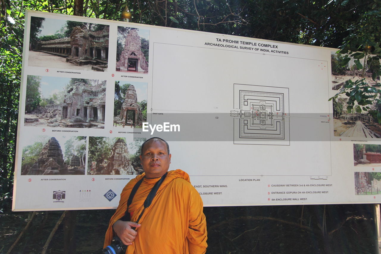 Portrait of monk standing against wall