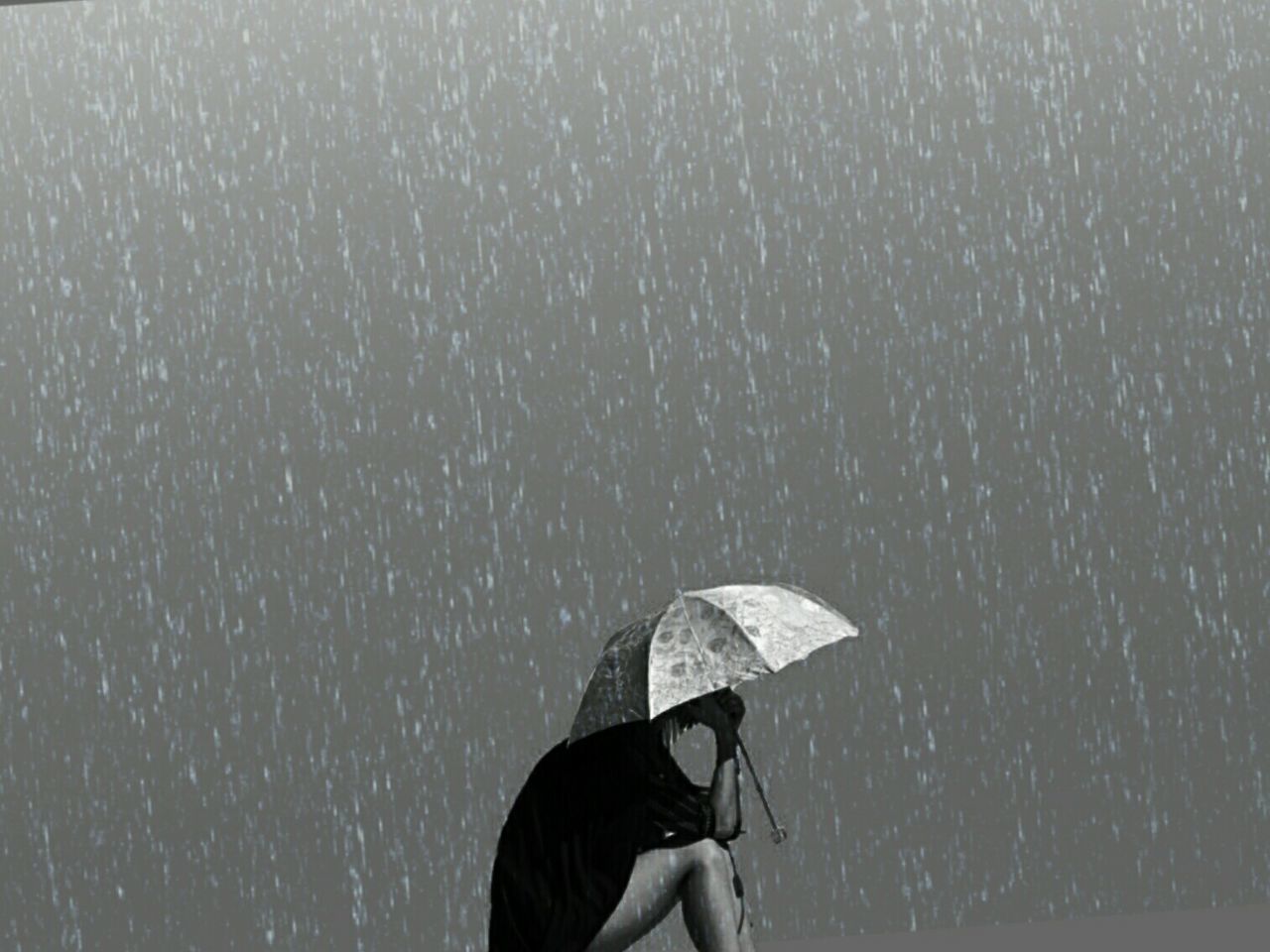 Woman with umbrella sitting outdoors during rainy season