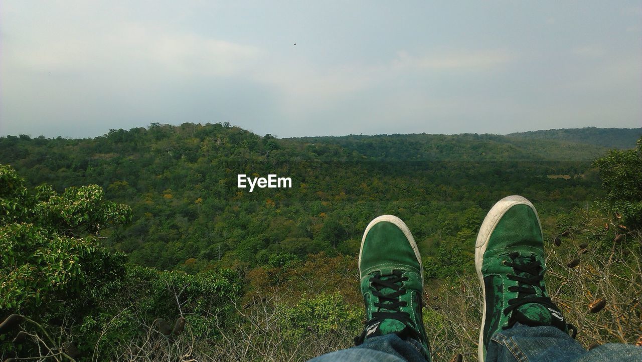 LOW SECTION OF MAN STANDING ON LANDSCAPE AGAINST SKY