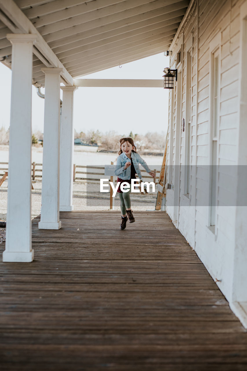 Happy young girl running on deck of patio outside