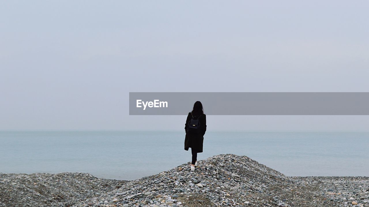 Rear view of woman standing on mountain against sea