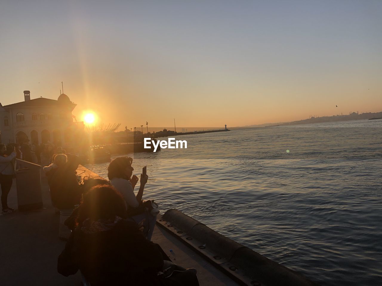 PEOPLE ON SEA AGAINST SKY DURING SUNSET