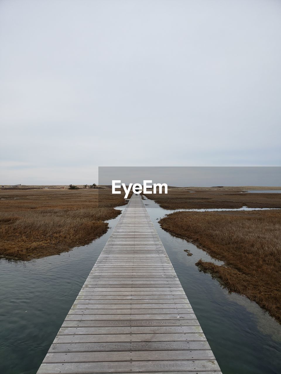 Boardwalk leading towards pier against sky