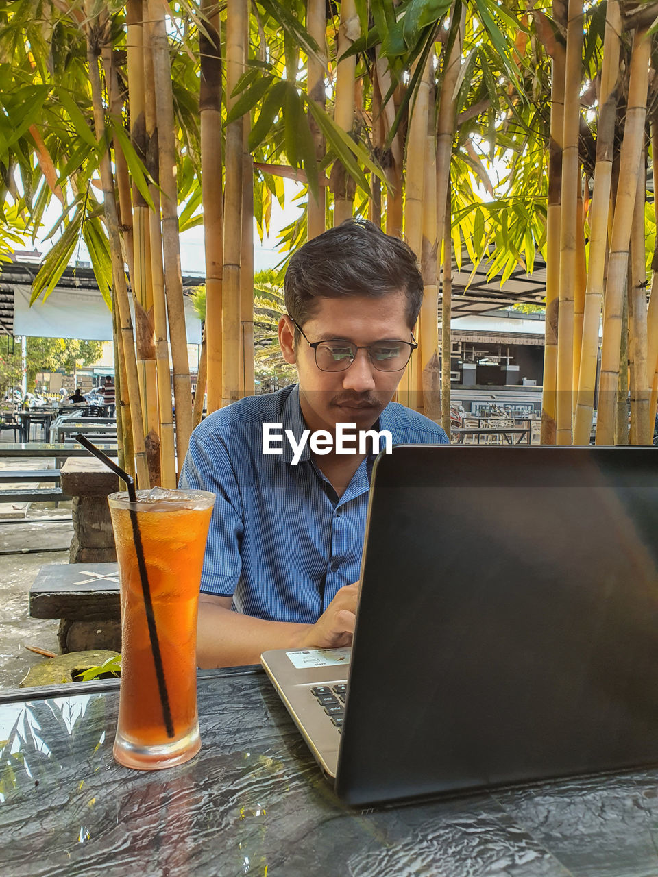 PORTRAIT OF YOUNG MAN SITTING ON TABLE AT RESTAURANT