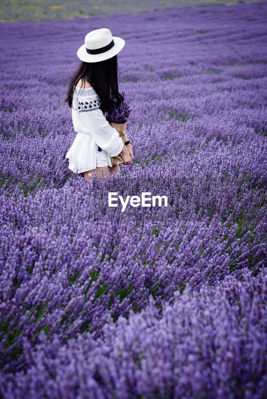 Full length of young woman with flowers on field