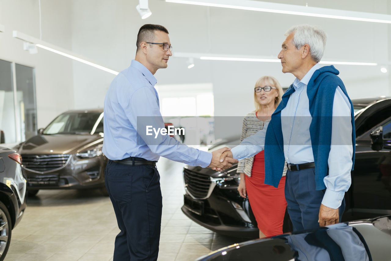 Senior couple couple talking with salesperson in car dealership