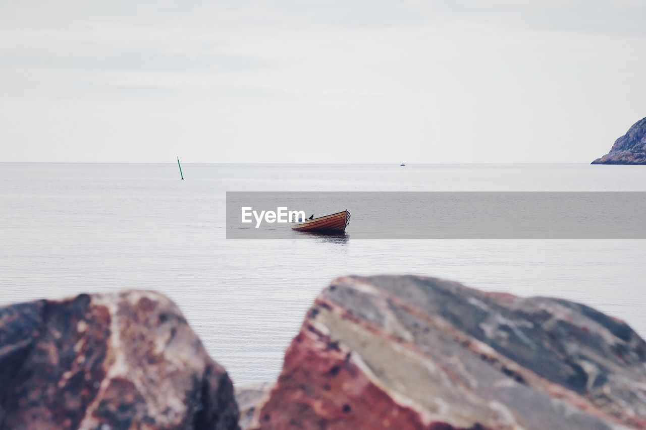 Boat on rock in sea against sky