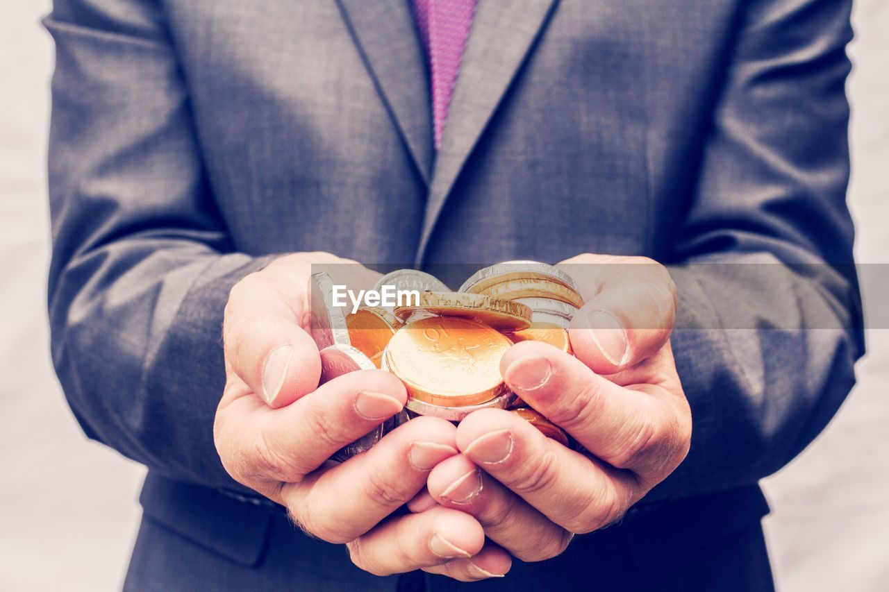 Midsection of businessman holding gold and silver coins