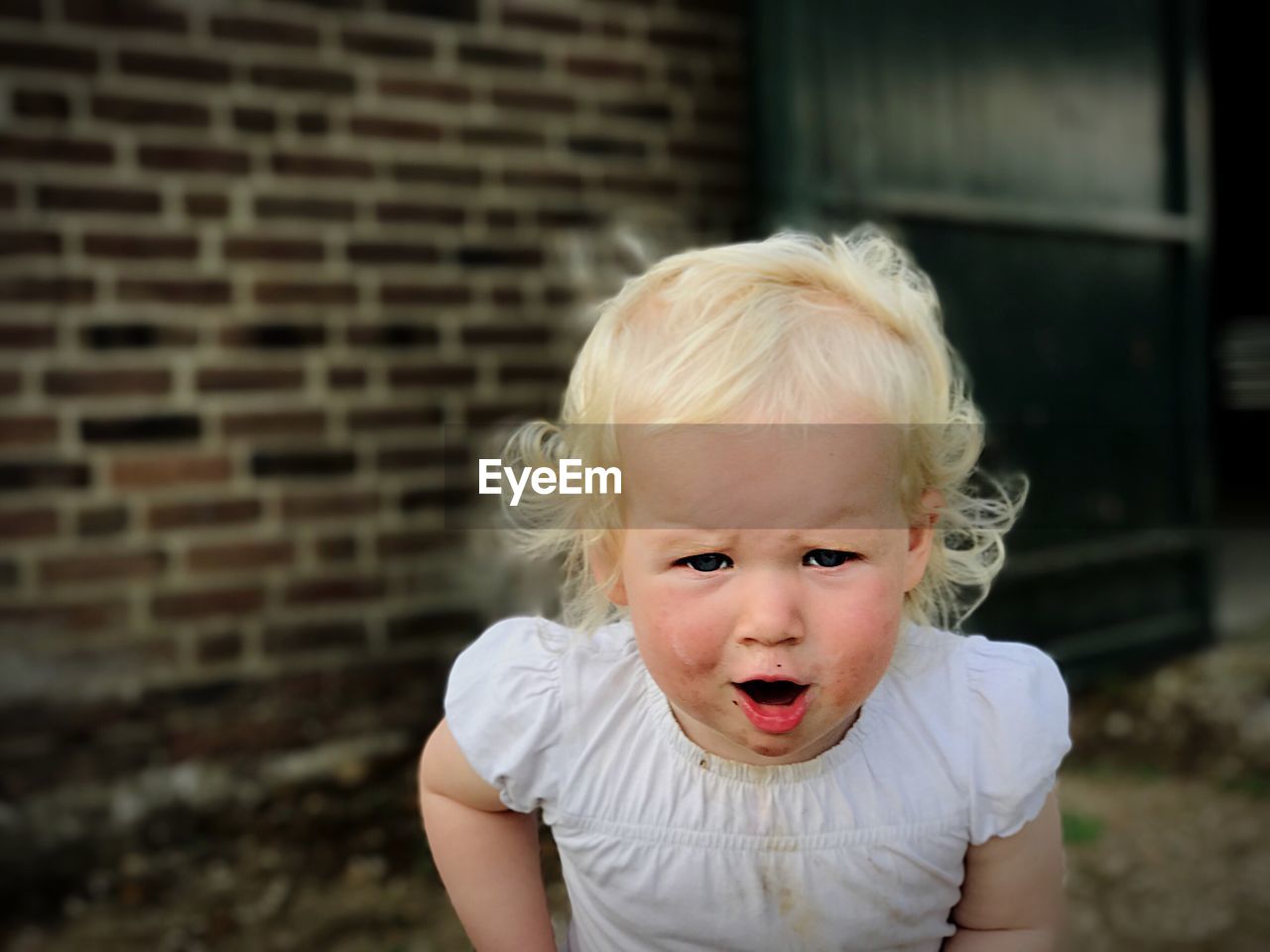 Portrait of cute girl against brick wall