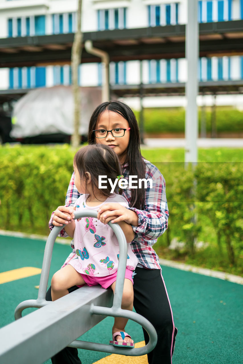 Portrait of sister playing with sibling at park