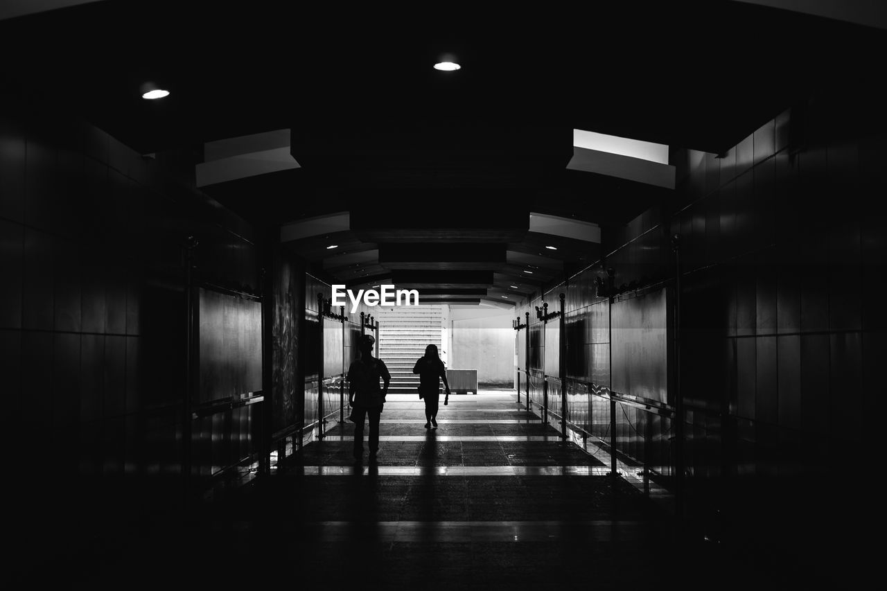 PEOPLE WALKING IN ILLUMINATED TUNNEL