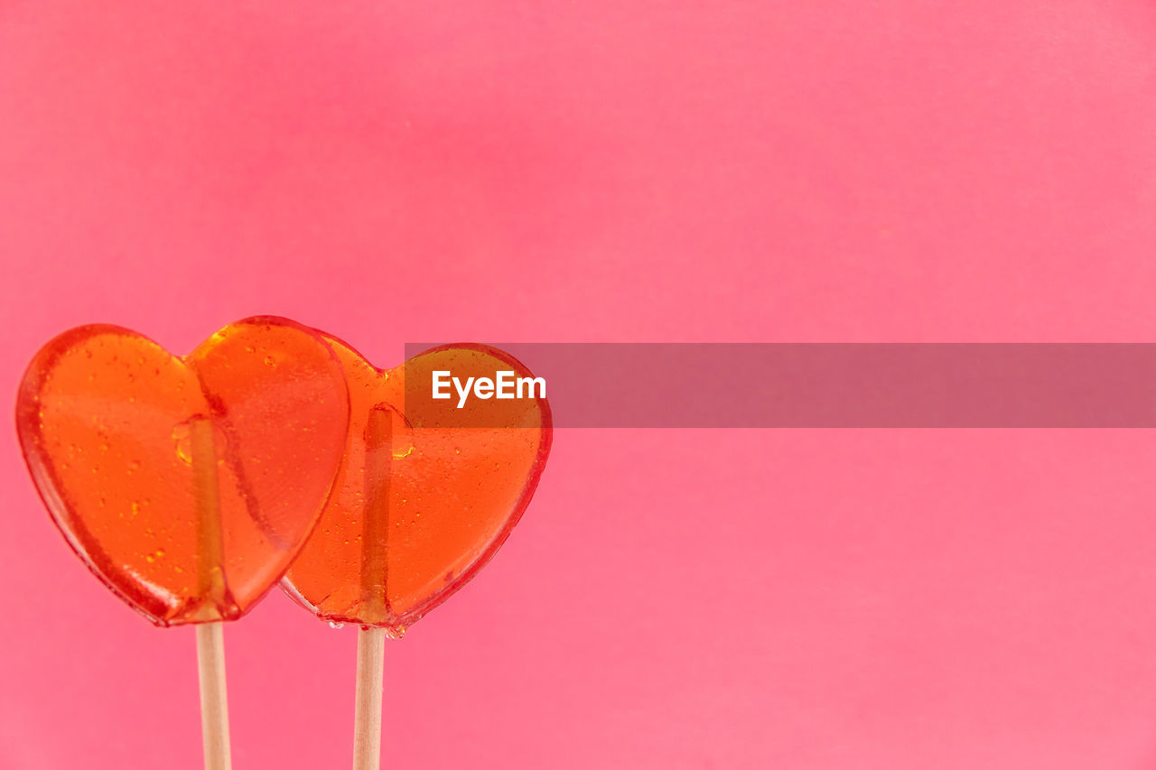 CLOSE-UP OF HEART SHAPE ON PINK AGAINST RED BACKGROUND