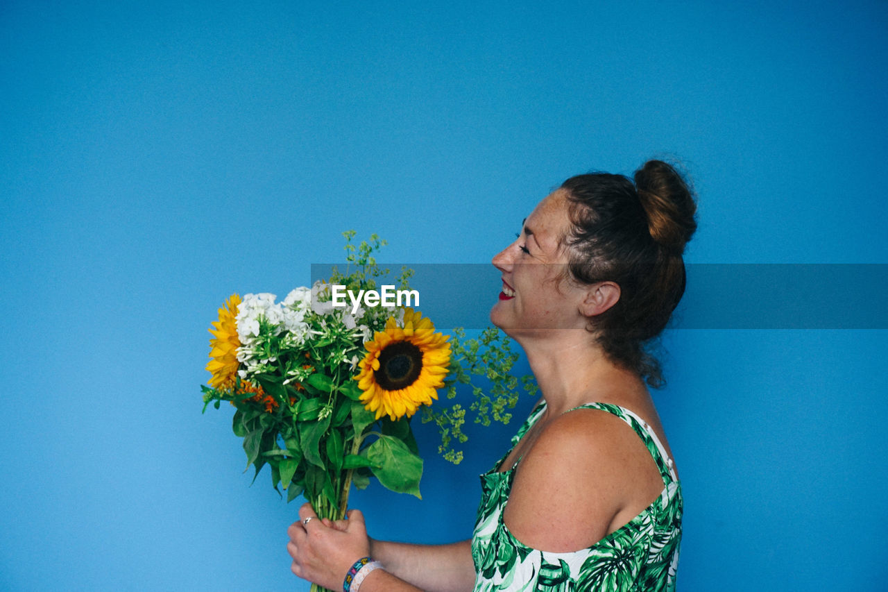 Woman holding flowers against blue background