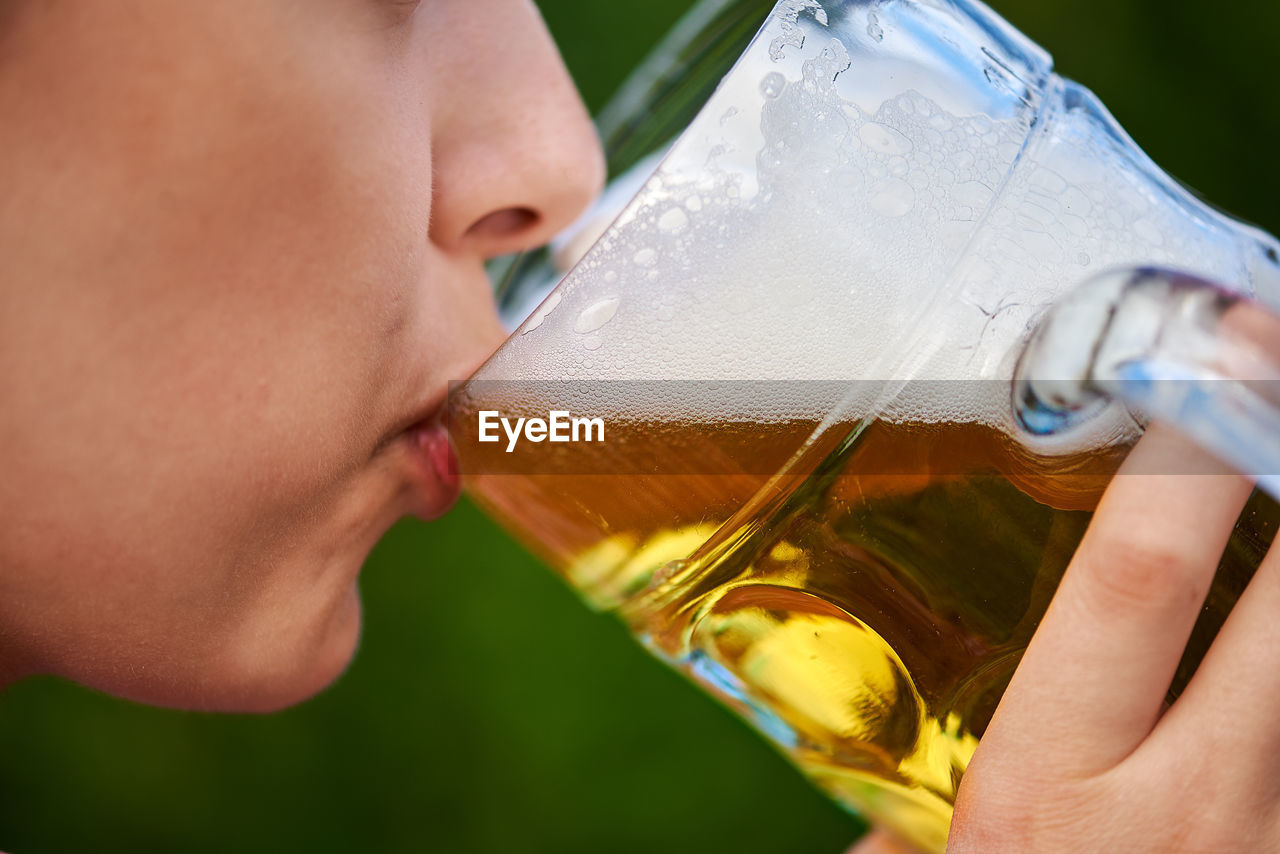 Close-up of woman drinking beer in glass