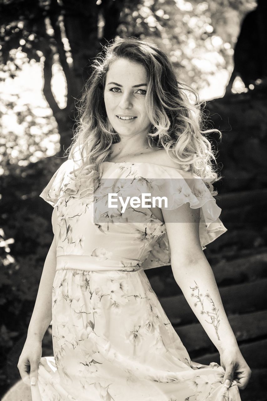 Portrait of beautiful young woman standing against trees in forest