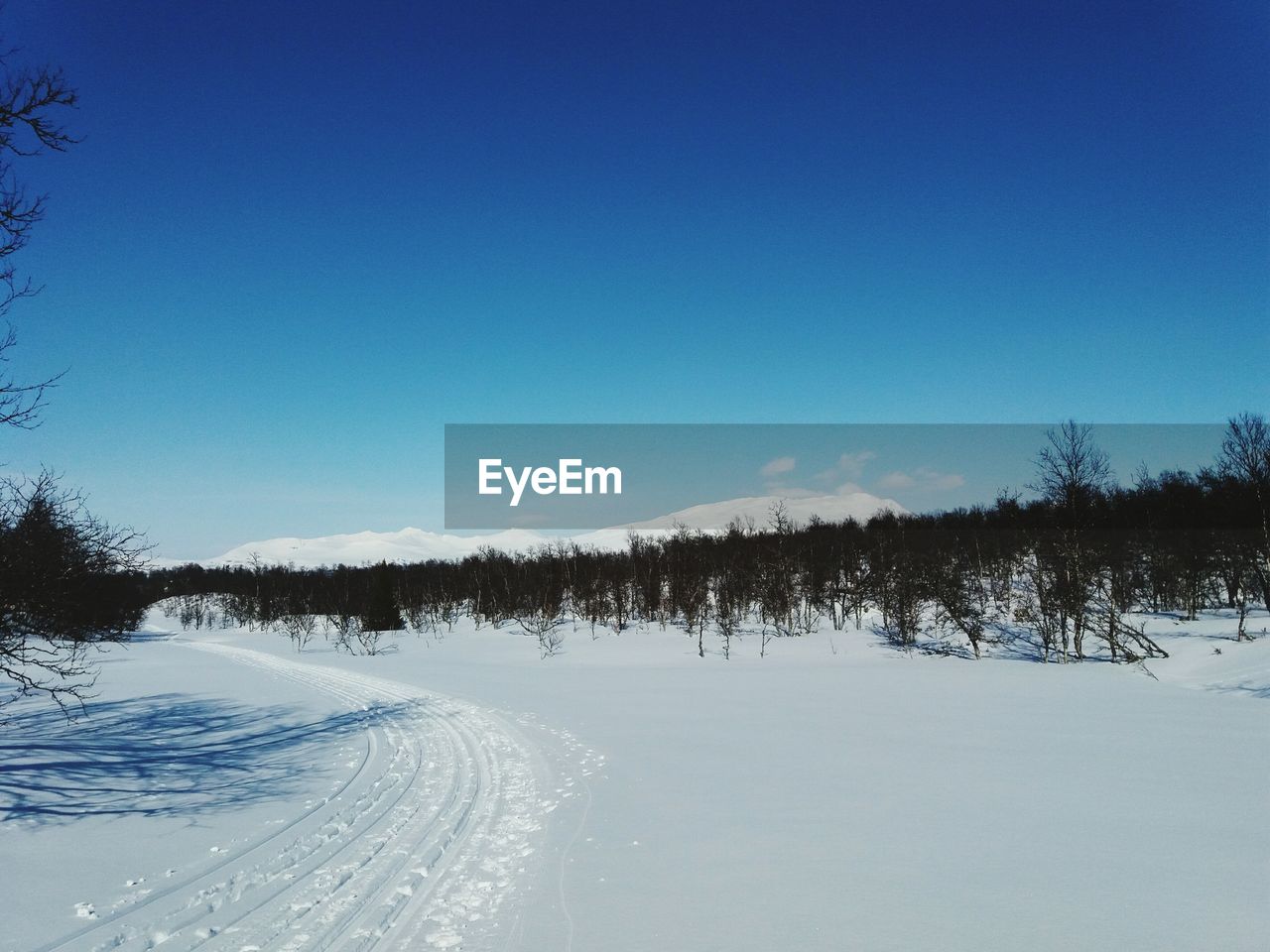 SNOW COVERED LANDSCAPE AGAINST BLUE SKY