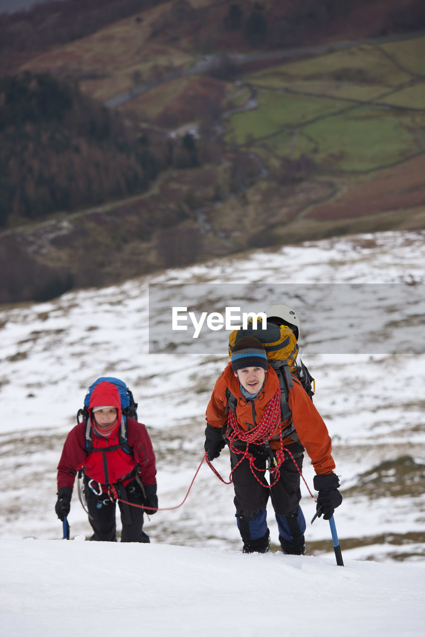 Couple hiking up helvellyn mountain in the winter