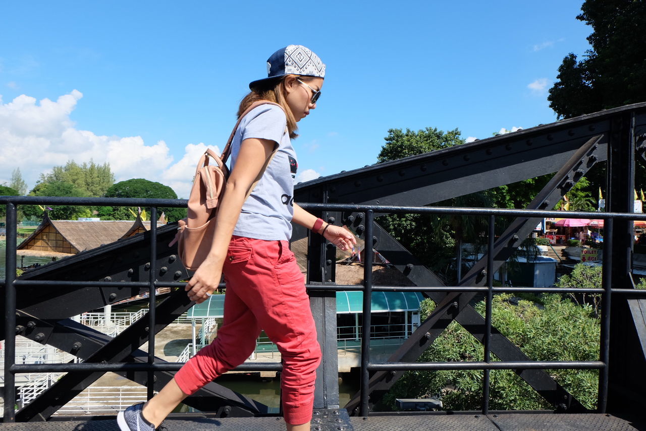 Side view of young woman walking on footbridge