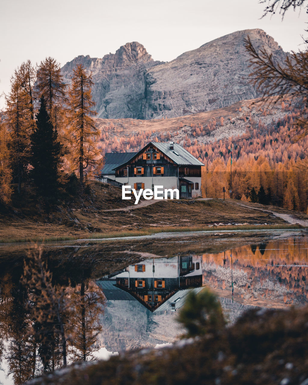 House by lake and mountains against sky