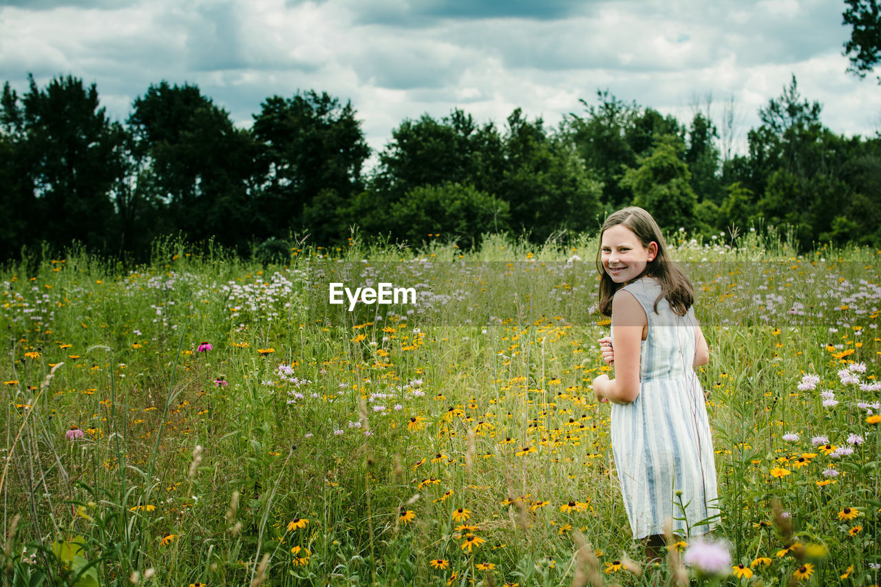 Teen girl smiling looking over her shoulder in a field of wild flowers