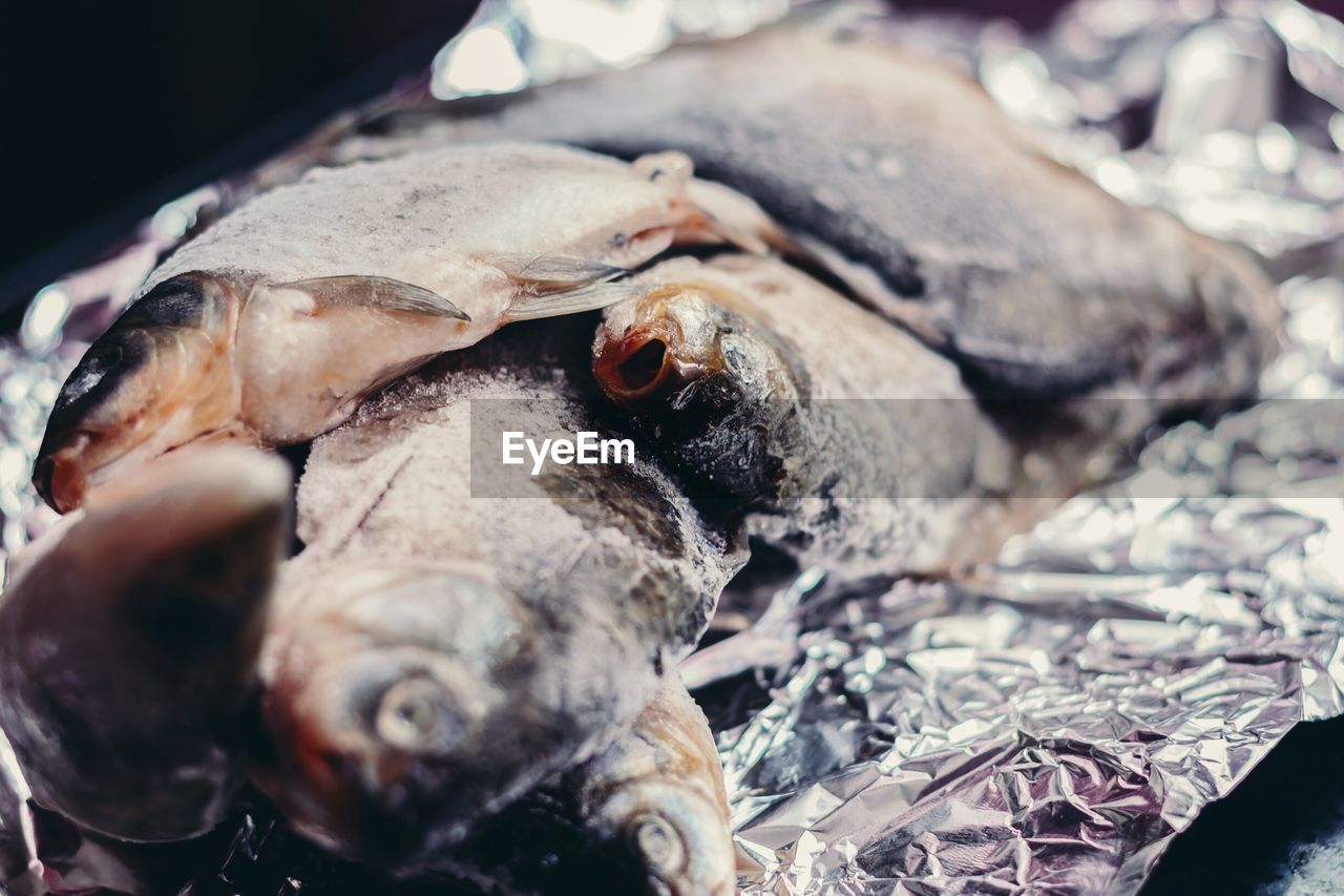 Close-up of frozen fish on foil for sale at market stall