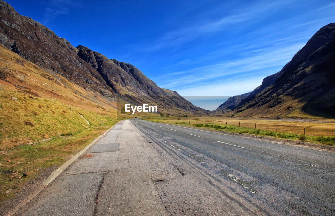 Road amidst landscape against blue sky