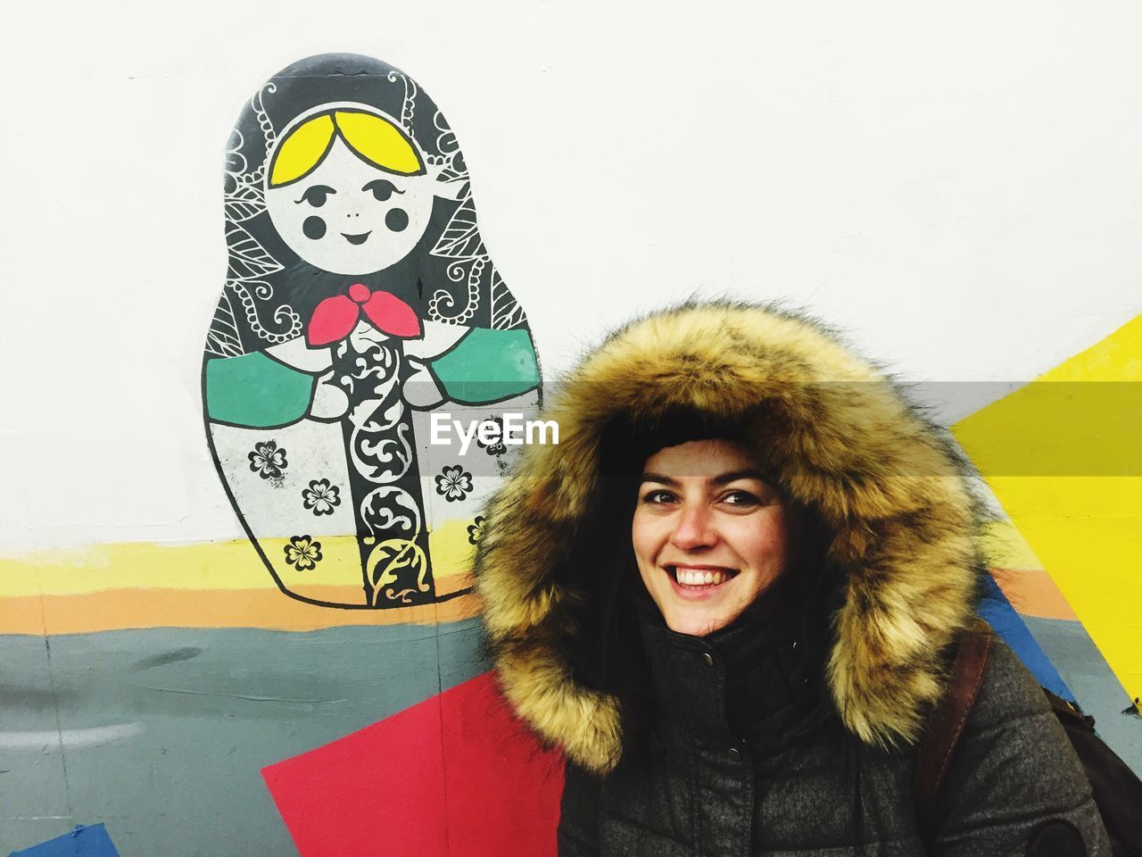 PORTRAIT OF HAPPY WOMAN STANDING AGAINST WALL