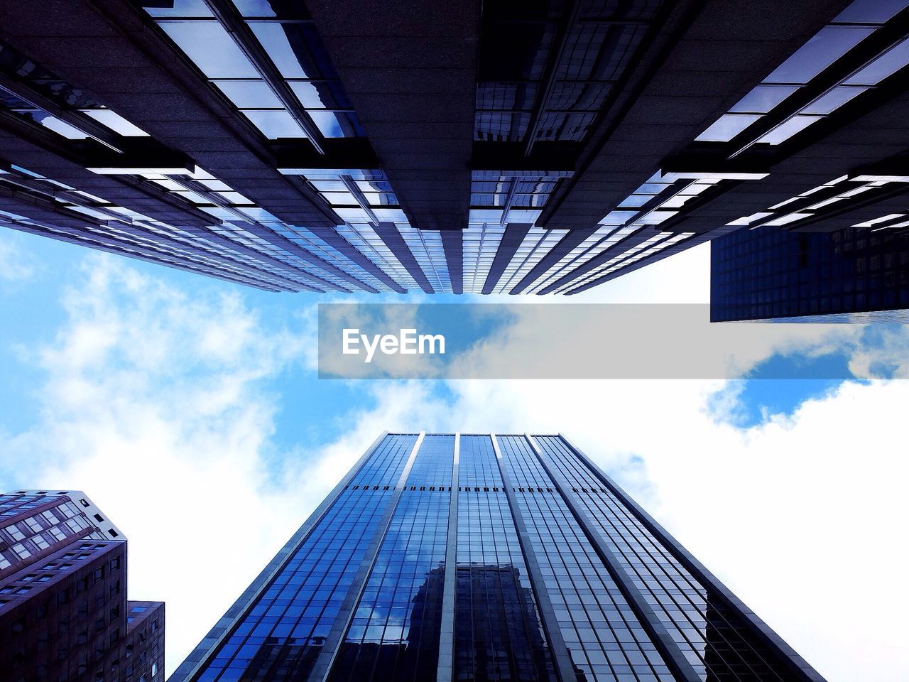 Directly below shot of skyscrapers against cloudy sky