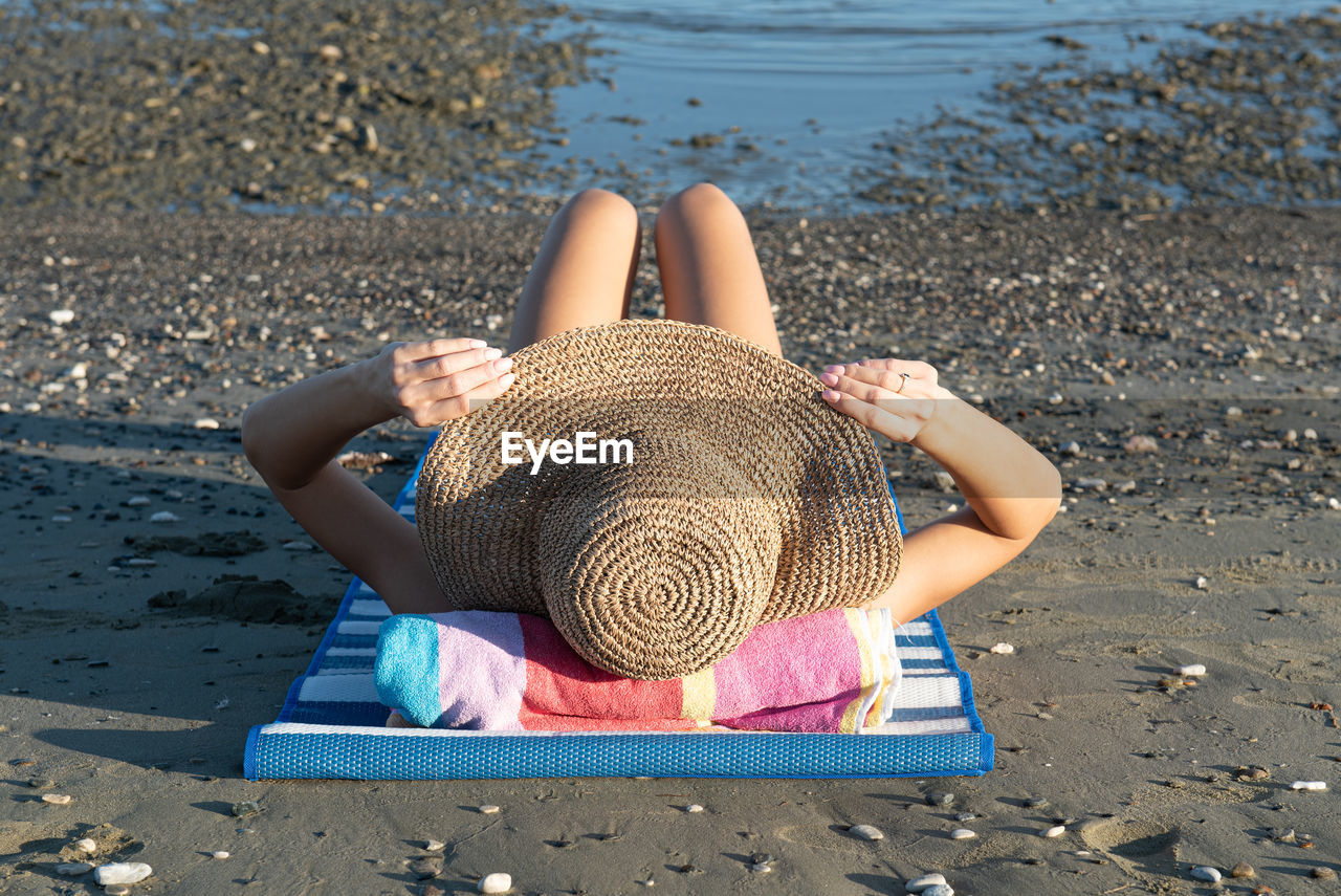 MIDSECTION OF WOMAN SITTING ON SAND