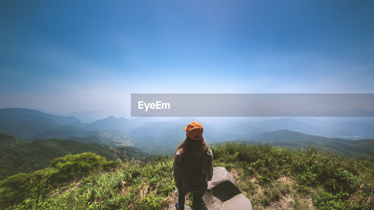 rear view of man walking on mountain against sky during sunset