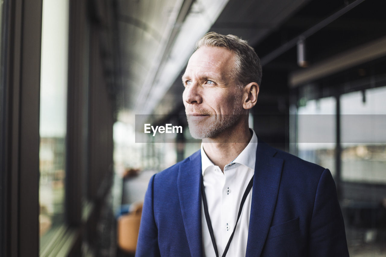 Male entrepreneur looking away while standing in office corridor