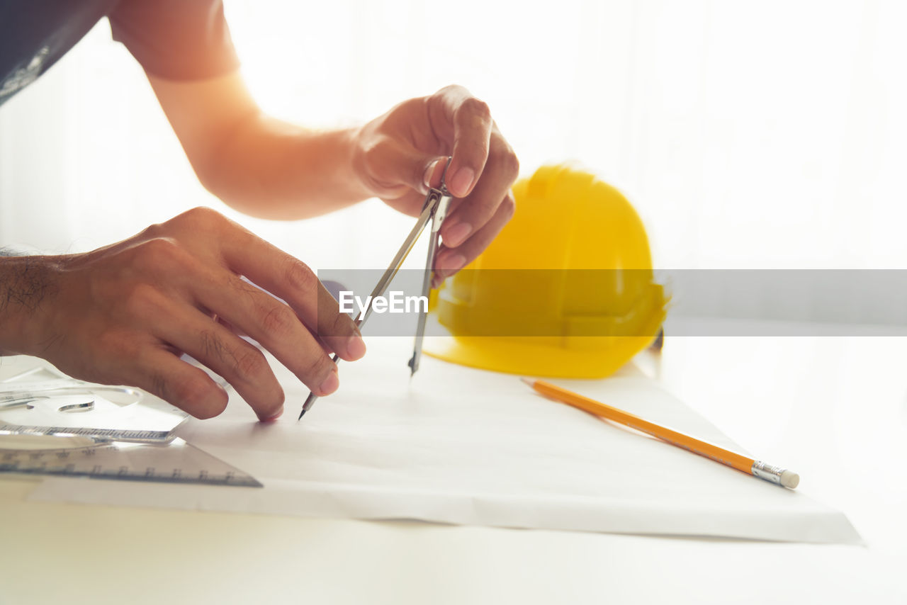 MIDSECTION OF PERSON WORKING ON TABLE WITH PAPER