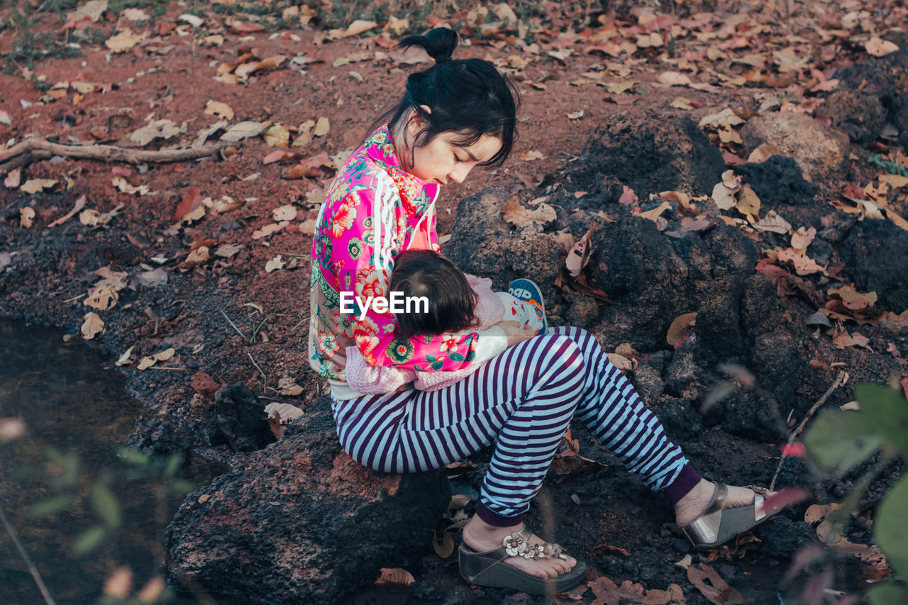 High angle view of mother with baby girl sitting on rock