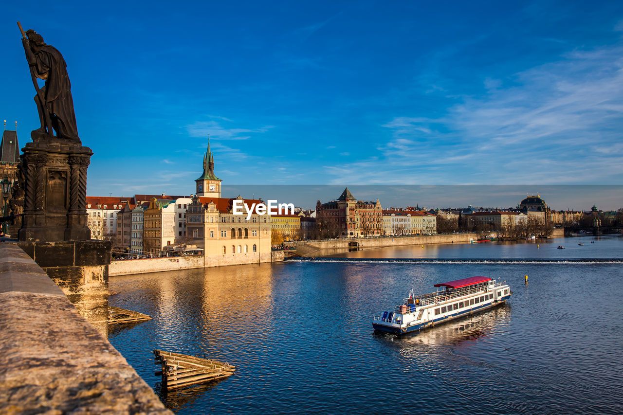 Boats in river against buildings in city