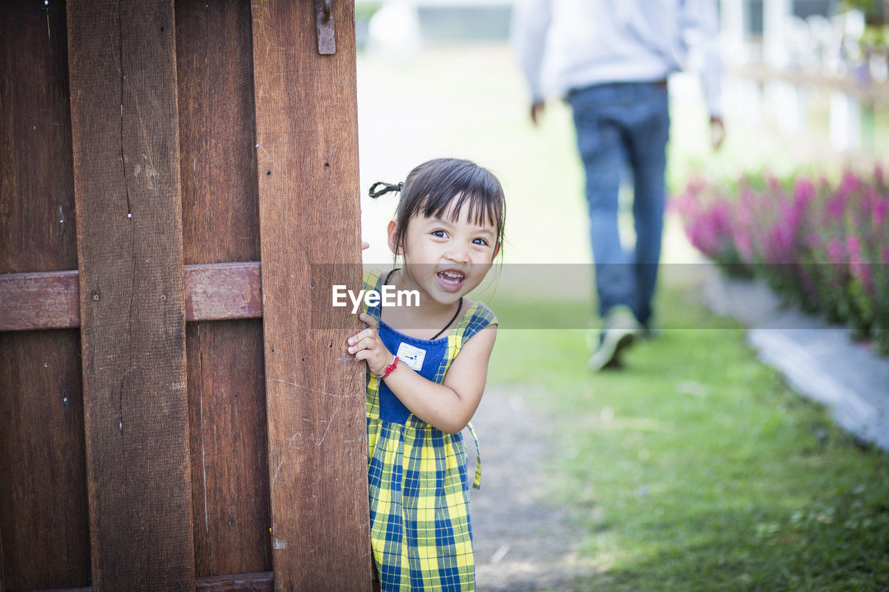 portrait of smiling young woman standing against fence