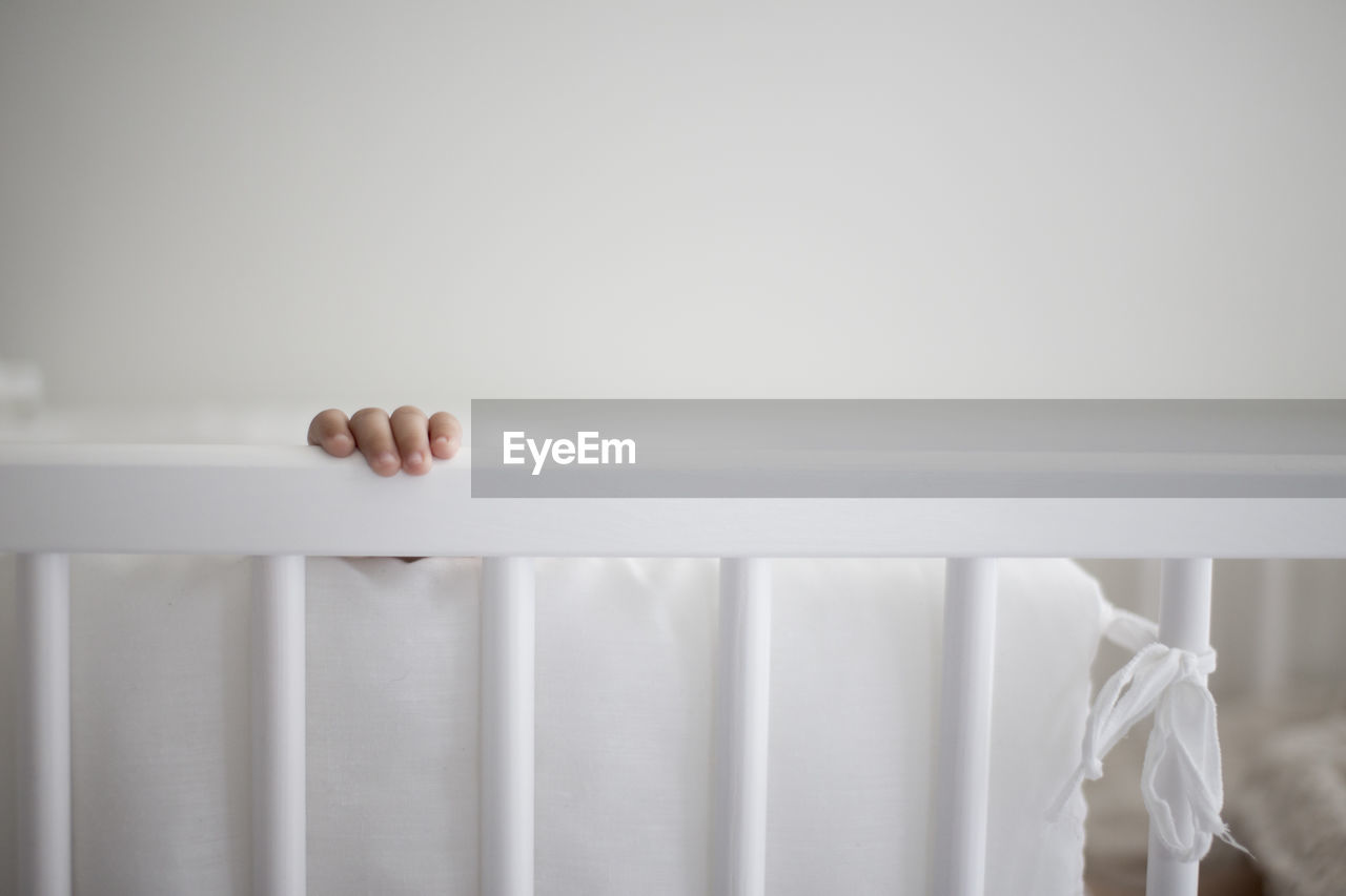 Cropped image of baby hand in crib at home