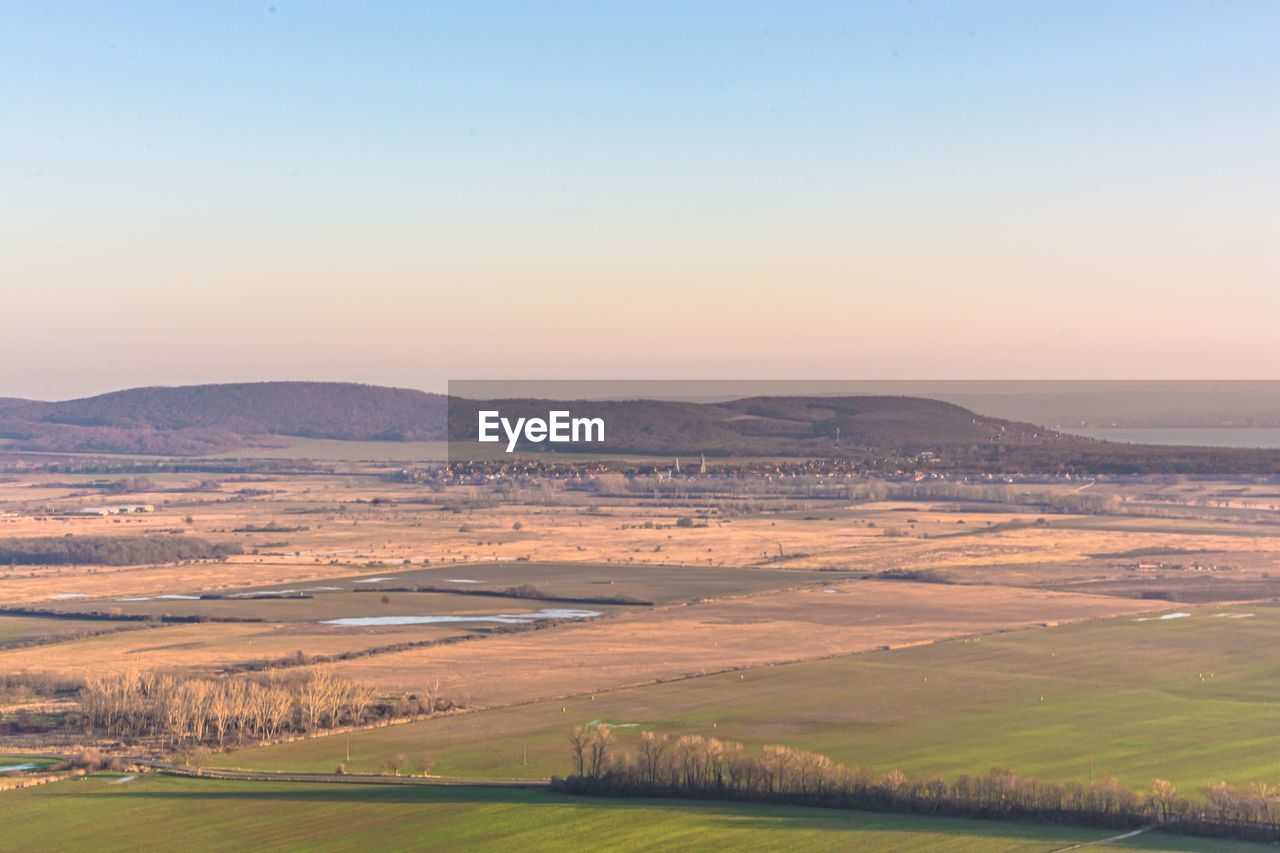 Scenic view of agricultural field against clear sky during sunset