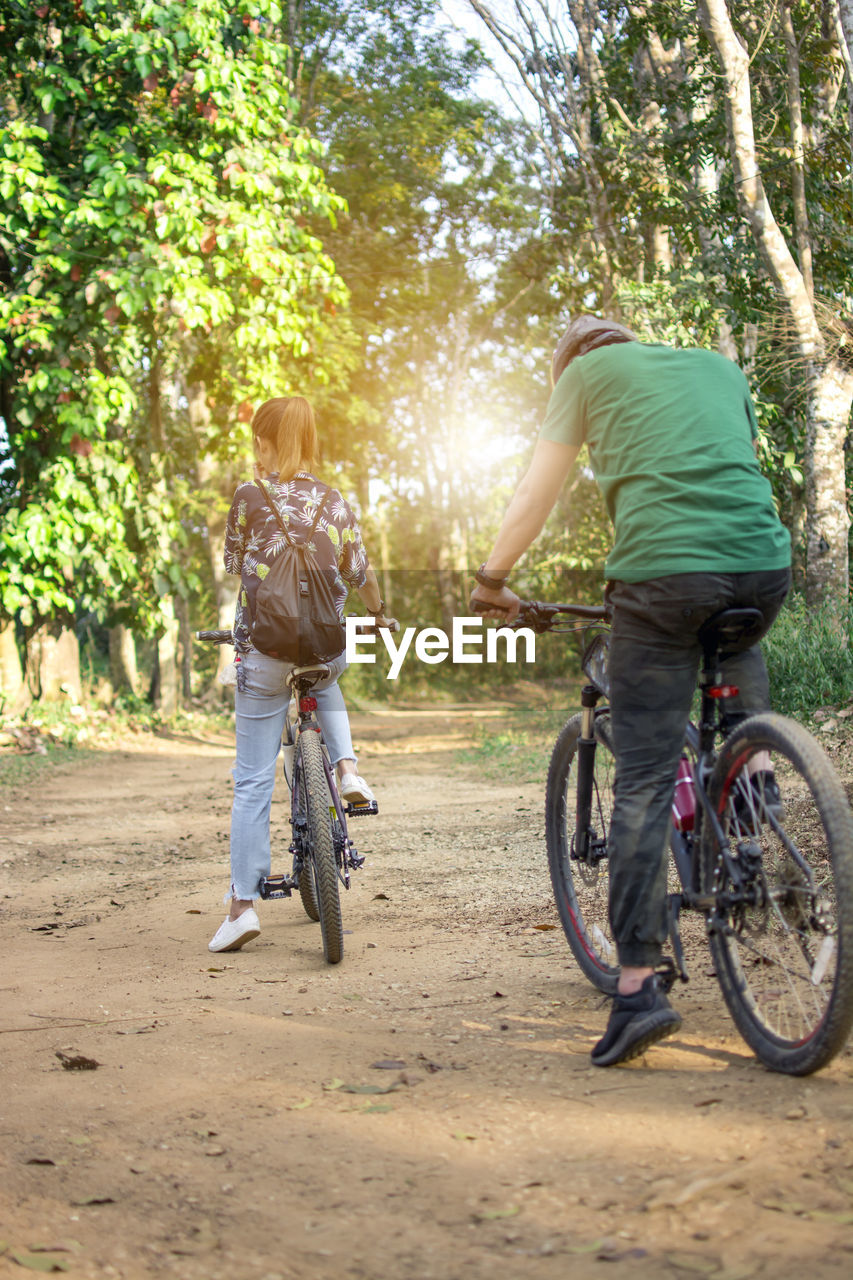 REAR VIEW OF MAN RIDING BICYCLE ON TREE