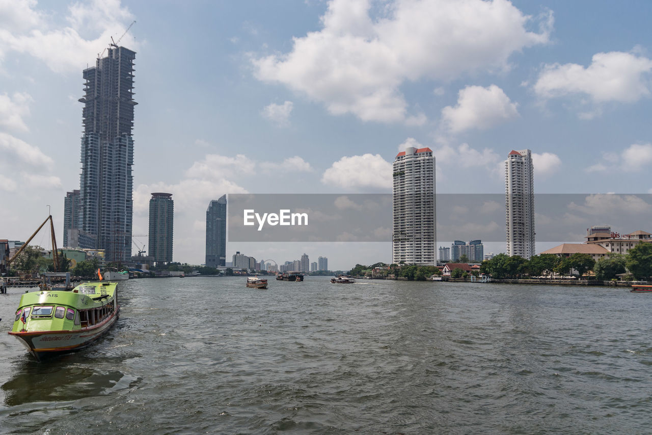 VIEW OF BAY AND BUILDINGS AGAINST CLOUDY SKY