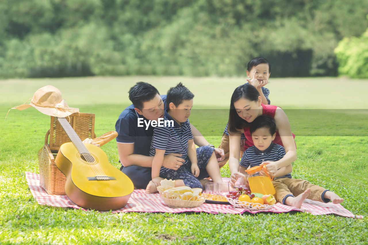 Happy family taking selfie while sitting on picnic blanket at park