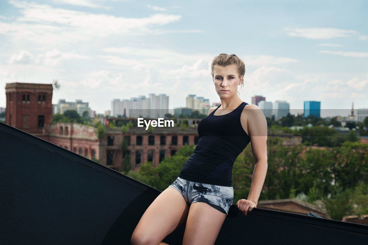 PORTRAIT OF YOUNG WOMAN AGAINST CITYSCAPE